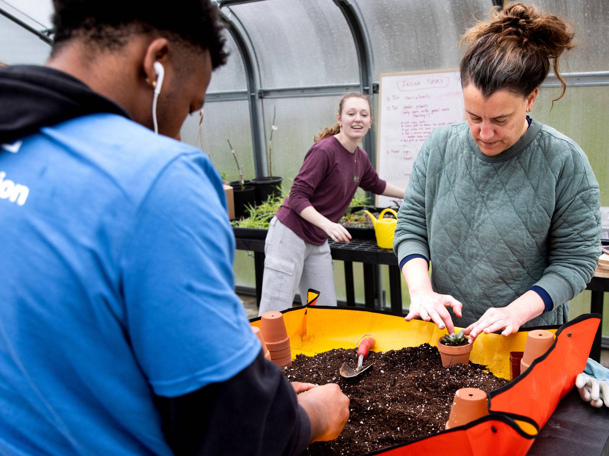 Staff and students work at garden bench while potting plants